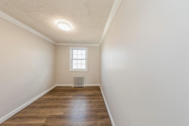 empty room featuring crown molding, radiator, dark wood-type flooring, a textured ceiling, and baseboards