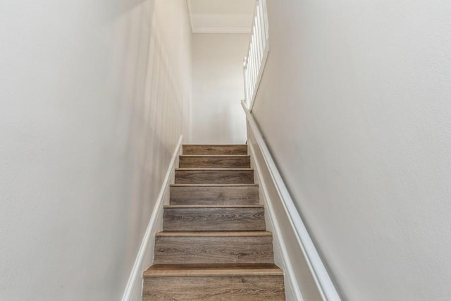 staircase with crown molding and wood finished floors