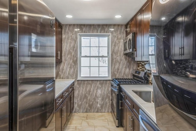 kitchen with marble finish floor, light stone counters, stainless steel appliances, and a sink