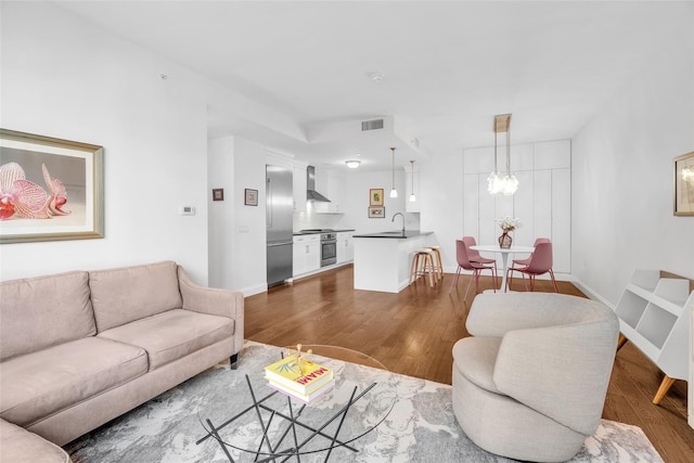 living room with dark wood-type flooring, a chandelier, visible vents, and baseboards