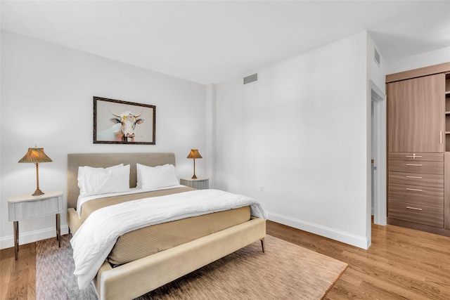 bedroom with light wood-style floors, baseboards, and visible vents