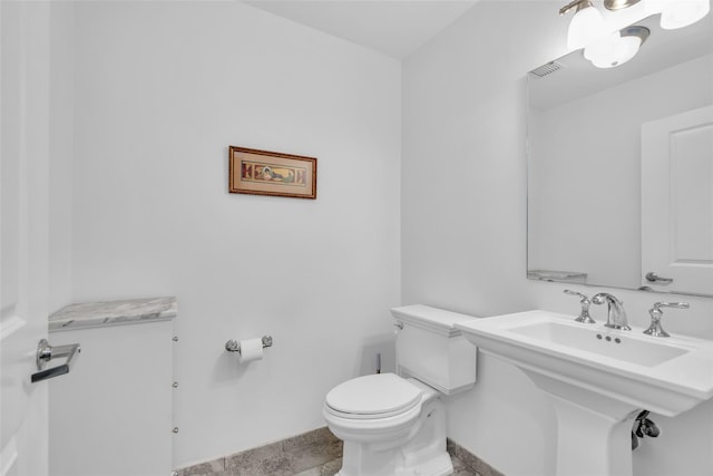 half bathroom with baseboards, visible vents, a sink, and toilet