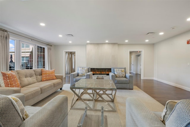 living area featuring a large fireplace, visible vents, baseboards, wood finished floors, and recessed lighting