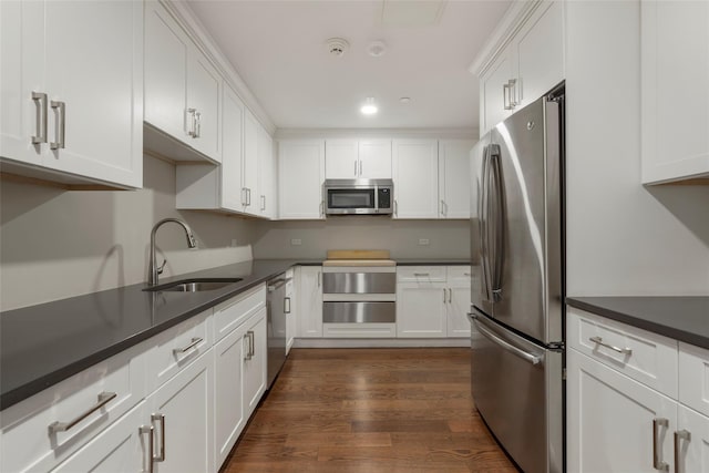 kitchen with appliances with stainless steel finishes, dark wood-style flooring, white cabinets, and a sink