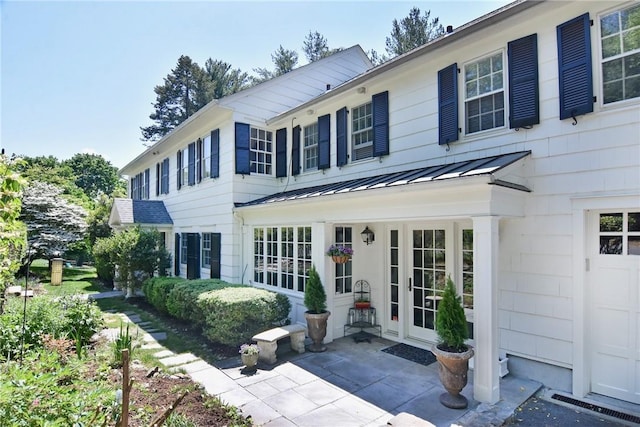 exterior space featuring a garage, metal roof, a standing seam roof, and a patio area