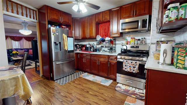 kitchen with wood finished floors, a sink, light countertops, appliances with stainless steel finishes, and tasteful backsplash