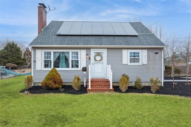 view of front facade with a chimney, a front lawn, solar panels, and roof with shingles