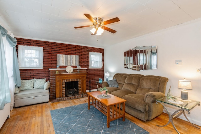 living room with brick wall, hardwood / wood-style floors, a fireplace, and a ceiling fan