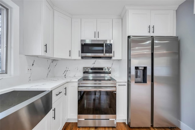 kitchen featuring stainless steel appliances, white cabinetry, and light stone countertops