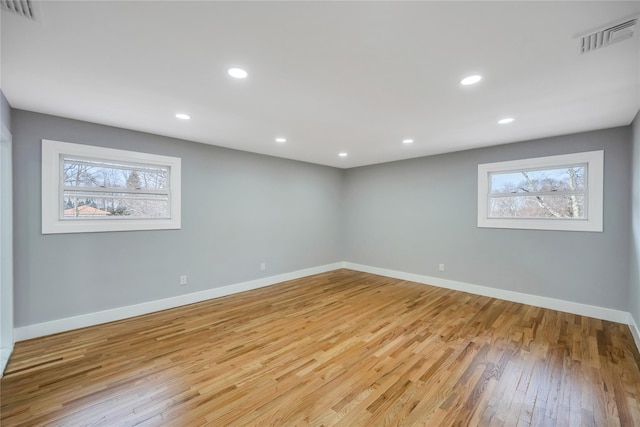 below grade area with light wood-style floors, visible vents, and baseboards