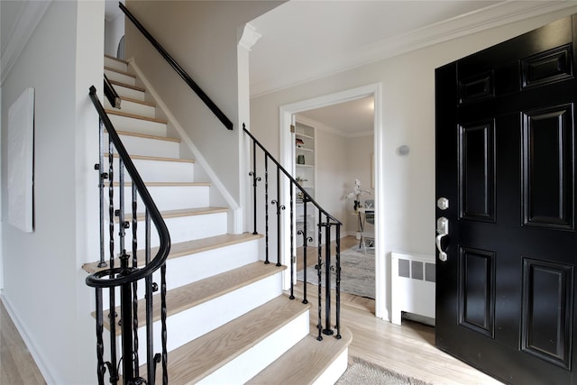 foyer with ornamental molding, light wood-style floors, stairway, and radiator heating unit