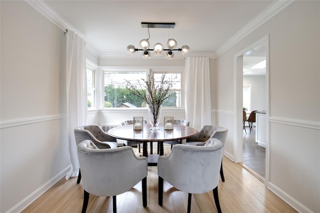 dining space featuring light wood finished floors, baseboards, ornamental molding, and a notable chandelier