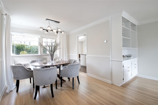 dining area with an inviting chandelier, light wood-style flooring, baseboards, and crown molding