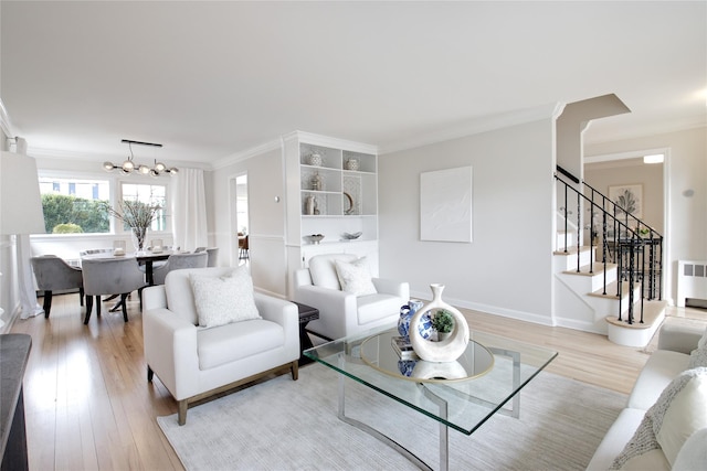 living area featuring a chandelier, light wood-style floors, stairs, ornamental molding, and radiator