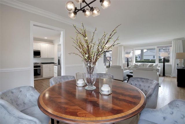 dining area featuring a notable chandelier, light wood-type flooring, and crown molding