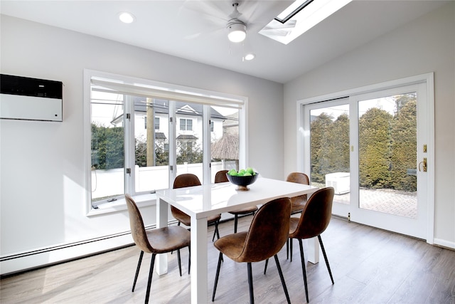 dining space featuring recessed lighting, baseboard heating, lofted ceiling with skylight, ceiling fan, and wood finished floors