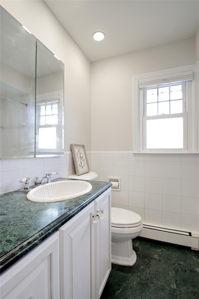 bathroom featuring a wainscoted wall, tile walls, a baseboard radiator, toilet, and vanity