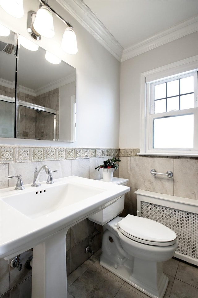 full bathroom with toilet, radiator heating unit, ornamental molding, tile patterned floors, and a shower stall