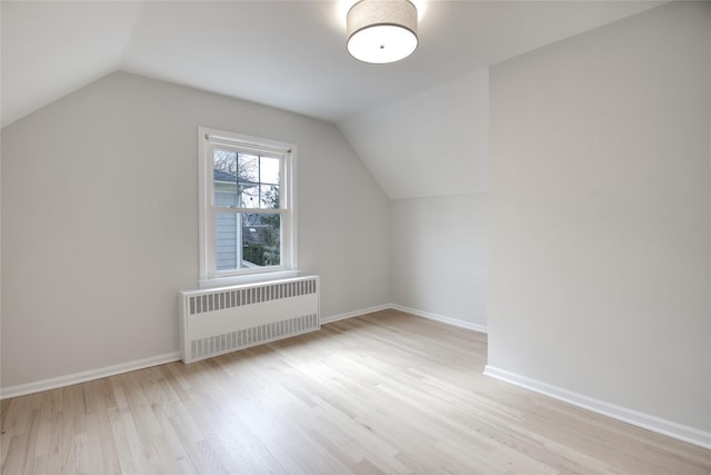 additional living space with lofted ceiling, radiator, baseboards, and wood finished floors