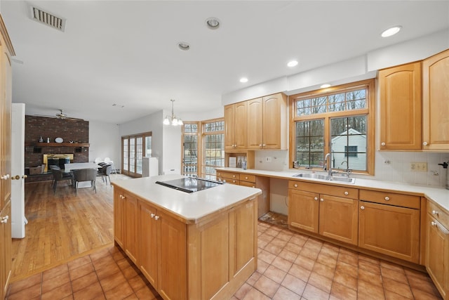 97 Ludlam Rd, Monroe, NY 10950 - kitchen with a sink, a kitchen island, black electric cooktop, light countertops, and decorative backsplash