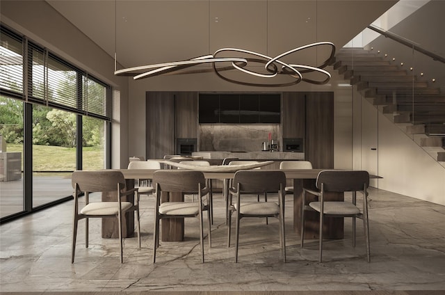 dining space featuring a towering ceiling, marble finish floor, stairway, and a notable chandelier