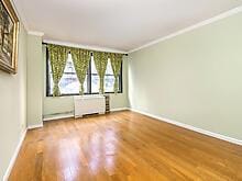 empty room featuring baseboards, crown molding, and wood finished floors