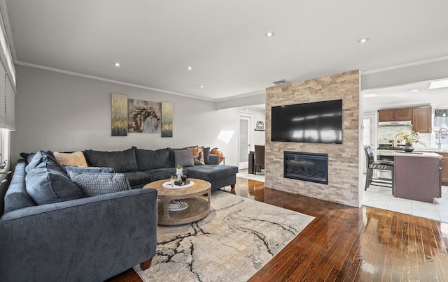 living room with light wood finished floors, a fireplace, recessed lighting, and crown molding