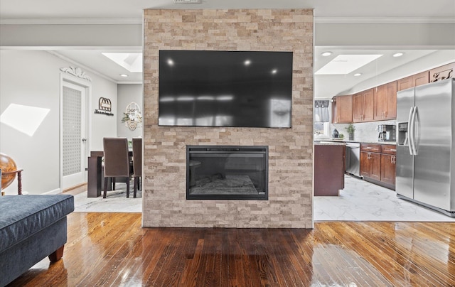 living area featuring recessed lighting, a large fireplace, crown molding, and light wood finished floors