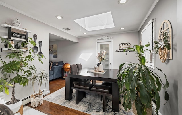 dining space featuring a skylight, visible vents, ornamental molding, wood finished floors, and recessed lighting