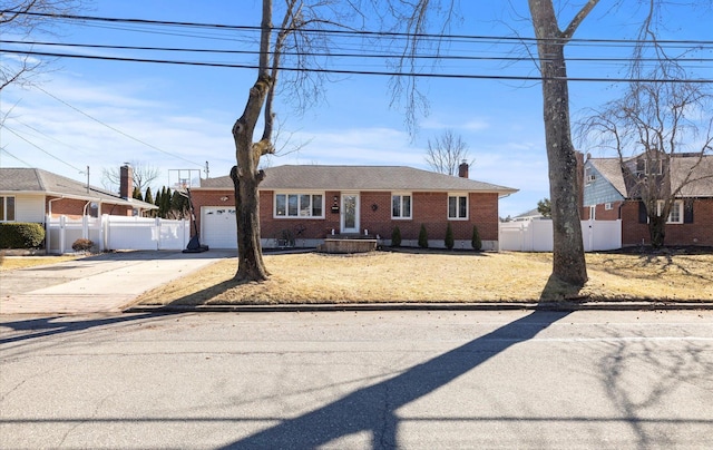 view of front facade with brick siding, a chimney, an attached garage, fence, and driveway