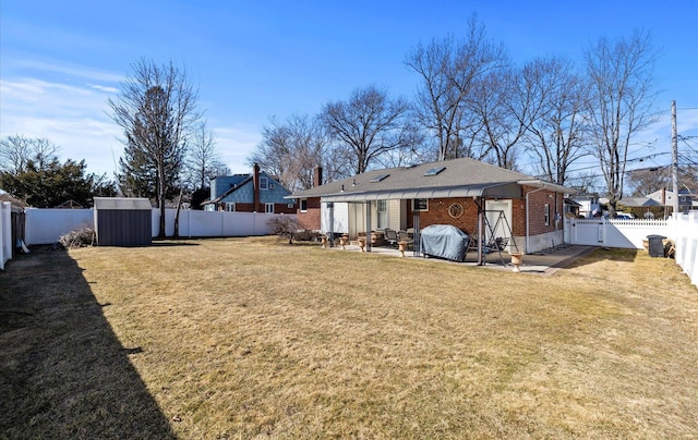 rear view of house with a yard, a fenced backyard, a gate, and brick siding