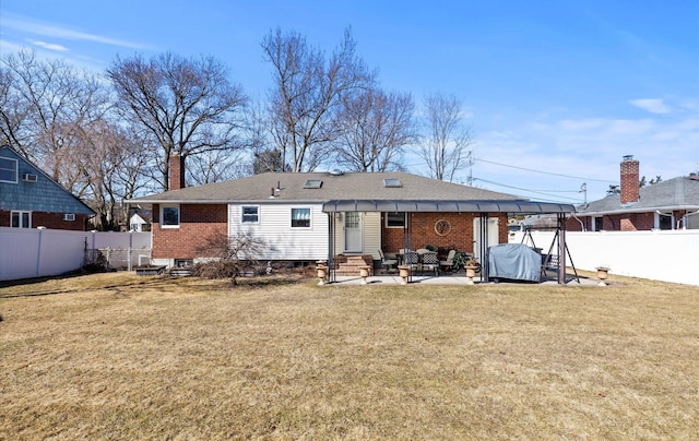 rear view of property featuring entry steps, a patio, a fenced backyard, brick siding, and a lawn