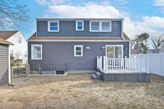 rear view of house featuring a deck, a lawn, and fence