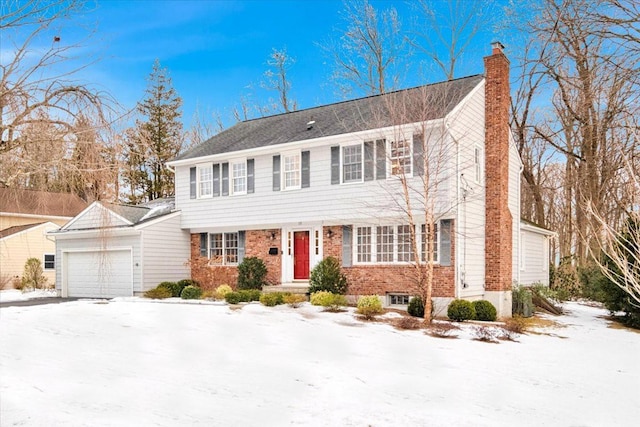 colonial home featuring brick siding, a chimney, and an attached garage