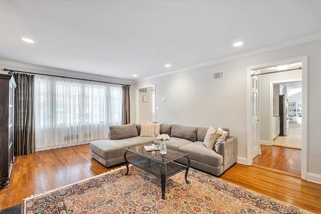 living room featuring light wood-style floors, visible vents, and crown molding