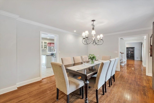 dining space with a chandelier, ornamental molding, and wood finished floors