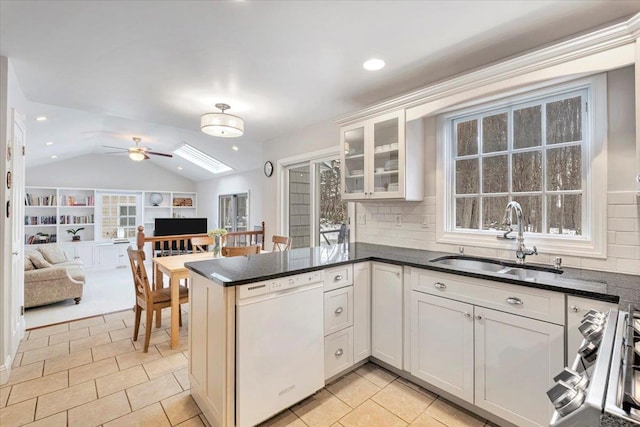 kitchen featuring a sink, white cabinets, open floor plan, dishwasher, and dark countertops