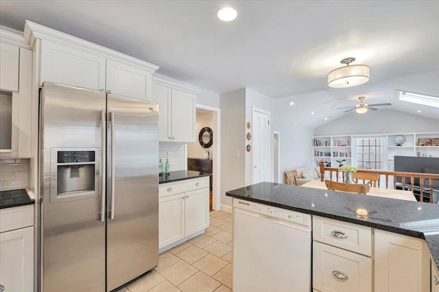 kitchen featuring dark stone counters, stainless steel refrigerator with ice dispenser, dishwasher, and open floor plan