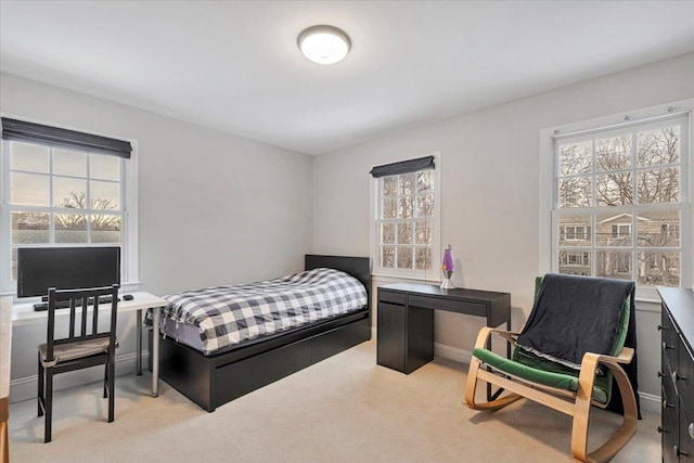 bedroom featuring light carpet, multiple windows, and baseboards