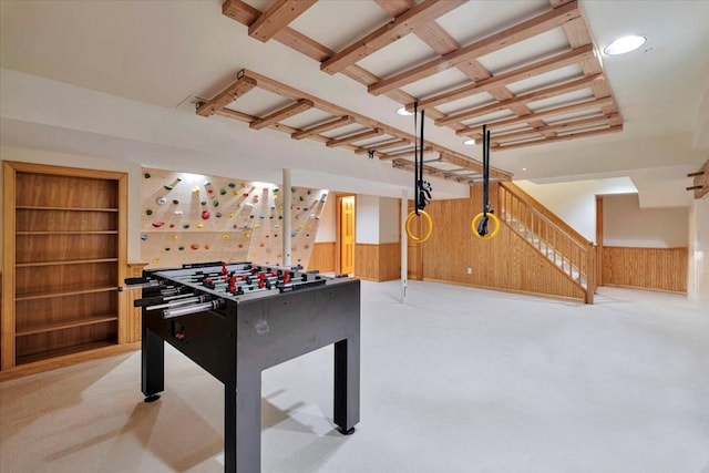 recreation room featuring wood walls, built in features, and wainscoting