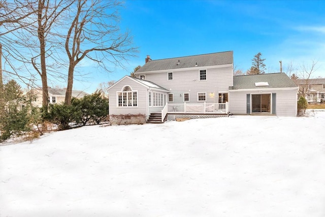 snow covered house with a chimney and a deck