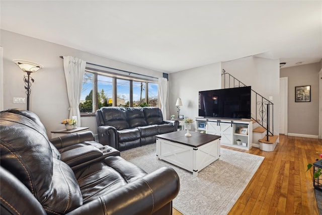 living room with stairs, light wood-style flooring, and baseboards