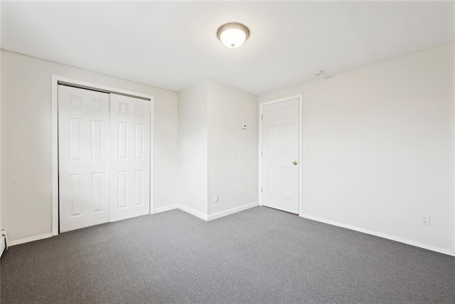 unfurnished bedroom with a closet, dark carpet, and baseboards