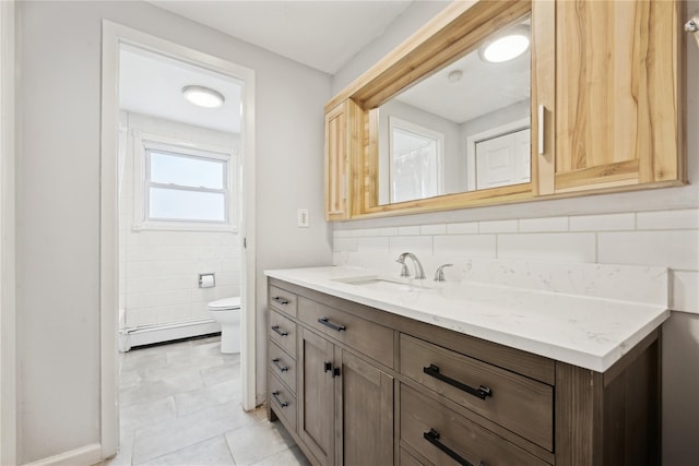 bathroom with tasteful backsplash, toilet, tile patterned floors, vanity, and a baseboard heating unit