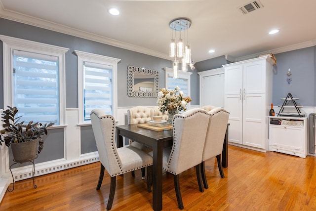 dining area with ornamental molding, visible vents, and light wood-style flooring