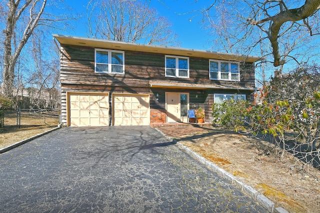 view of front facade with driveway, a garage, and fence