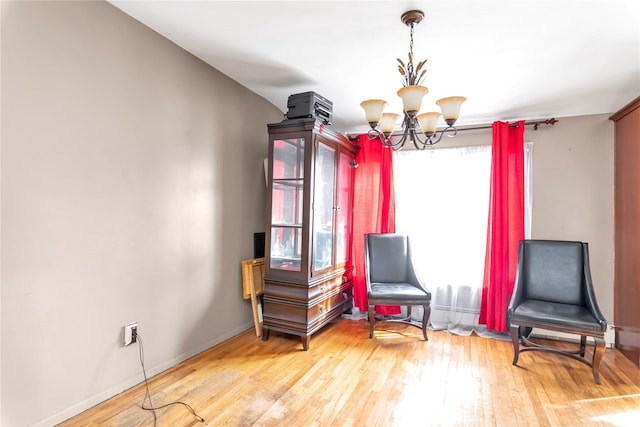 living area with wood-type flooring, baseboards, and a chandelier