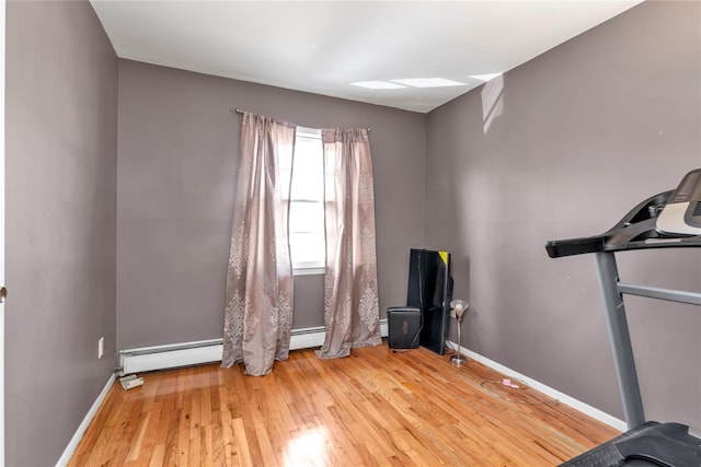 workout area featuring a baseboard heating unit, baseboards, and hardwood / wood-style flooring