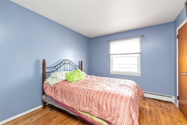 bedroom with a baseboard radiator, baseboards, and wood finished floors