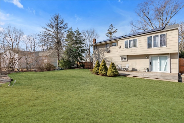 back of property featuring a fenced backyard, a chimney, solar panels, and a yard